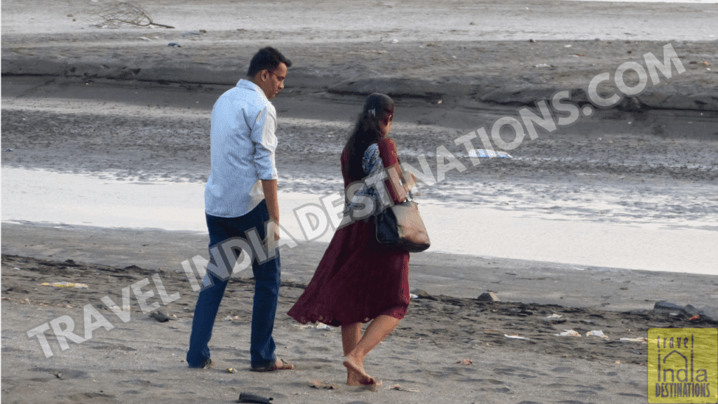 A shot of a couple having conversation as they walk the Vasai Suruchi beach.