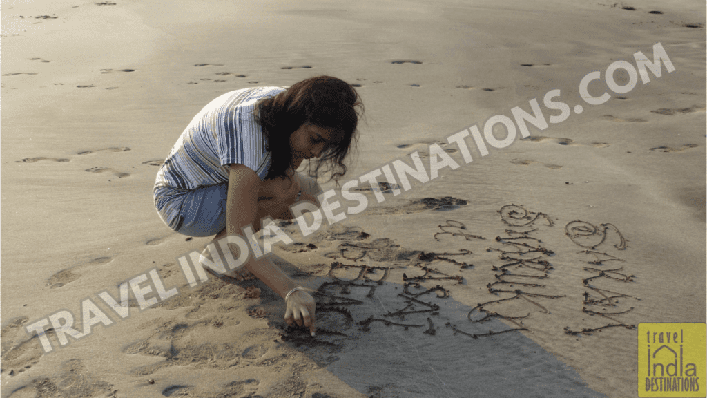 A woman writing name on the sand at Suruchi Beach Vasai