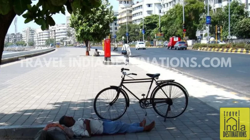 a man sleeping under the shade of a tree at marine drive mumbai during afternoon hours