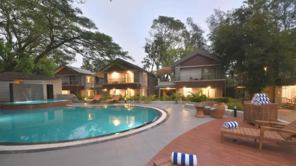 Arova Woods by the Fern Lonavala – wooden cabin-style hotel surrounded by greenery and outdoor swimming pool and sun loungers for winter holidays.