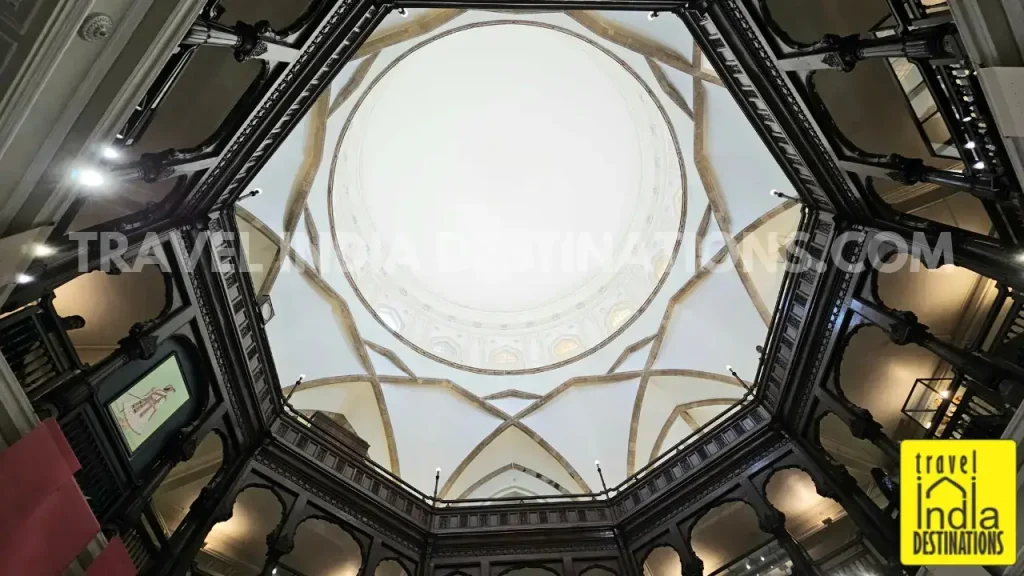 Looking up from the centre of the Rotunda at Chhatrapati Shivaji Maharaj Vastu Sangrahalaya, with wooden first-floor railings, arches, and the white dome filtering in soft daylight.