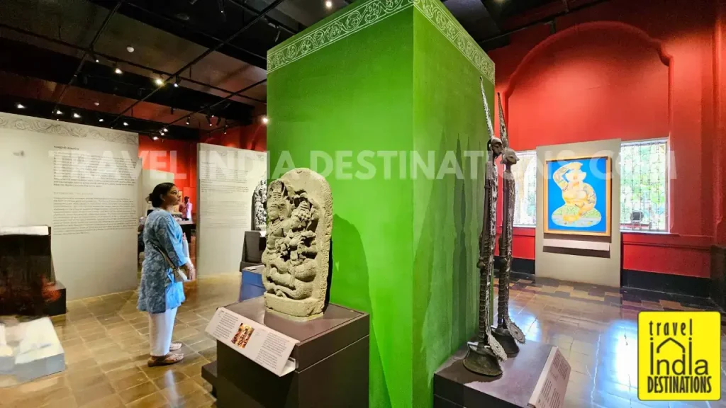 A visitor admiring a stone sculpture inside the Sculpture Gallery at CSMVS, with multiple exhibits visible across the hall.