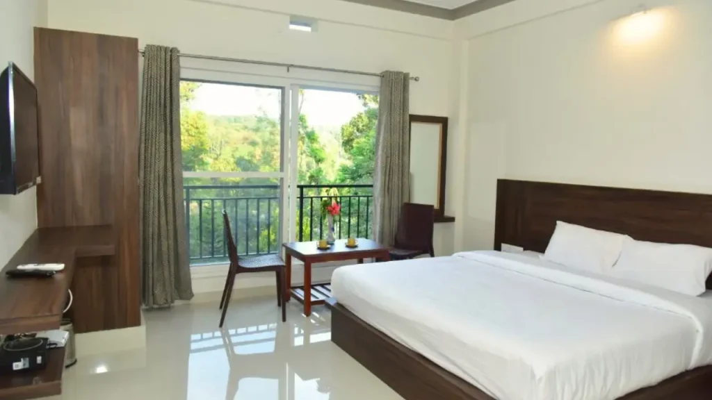 A picture of the interiors of King Room with balcony at Grand Mistry Heaven one of the best budget hotels in Madikeri Coorg.