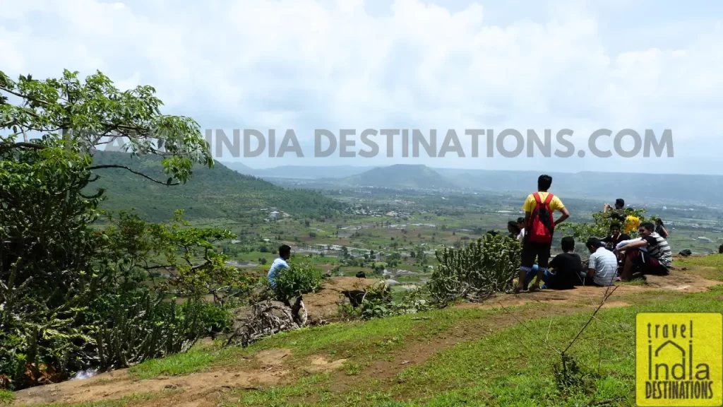 Hikers taking a break and enjoying panoramic views of the Sahyadris near Lohagad Fort. 