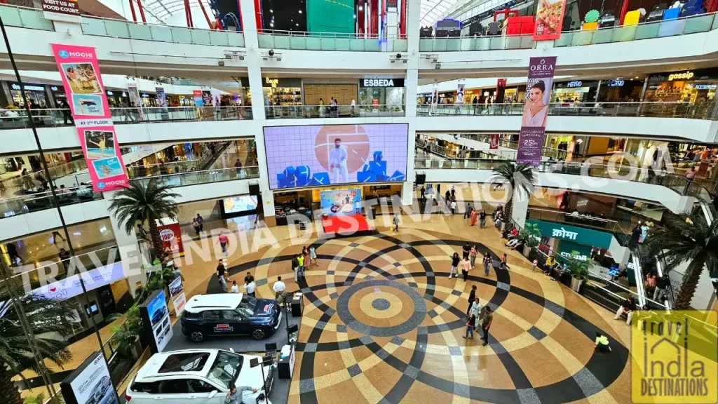 Spacious round lobby of Infinity Mall 2 featuring parked exhibition cars and large TV panels displaying promotional ads