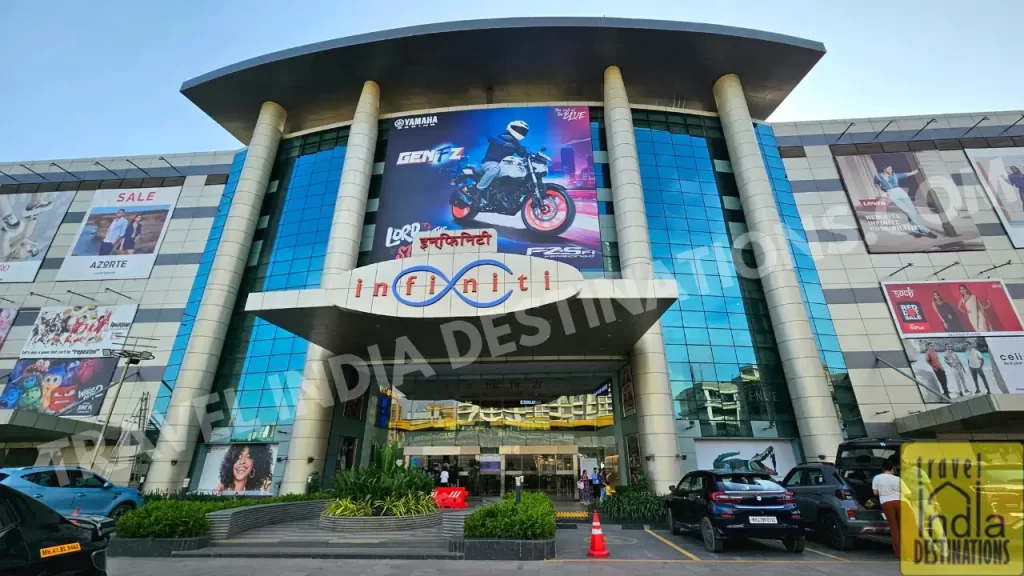 Massive glass facade of Infinity Mall 2 with visible car parking area at the entrance, one of the best shopping malls in western suburbs of Mumbai