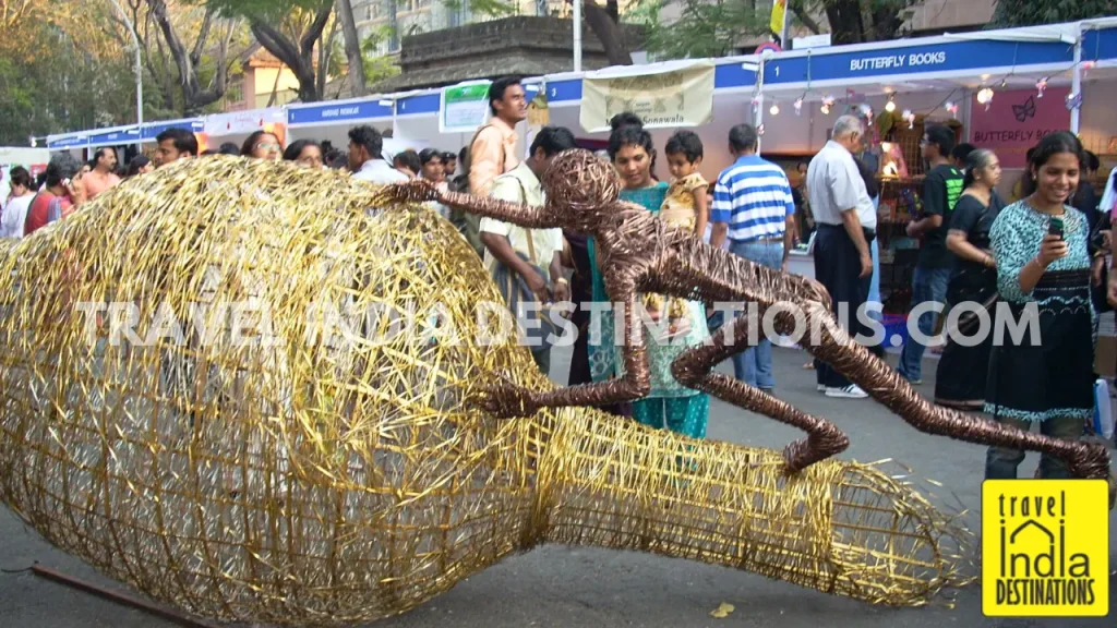 Visitors admiring and interacting with a giant Baya weaver nest installation at Kala Ghoda Arts Festival.