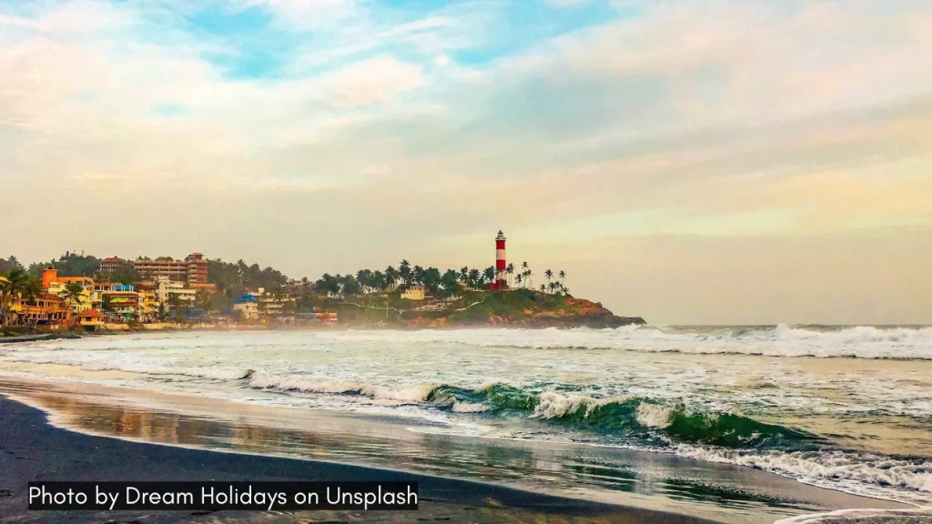 A shot of Kovalam lighthouse and the beach along with waves and clear blue sky ideal for honeymoon in February in India.