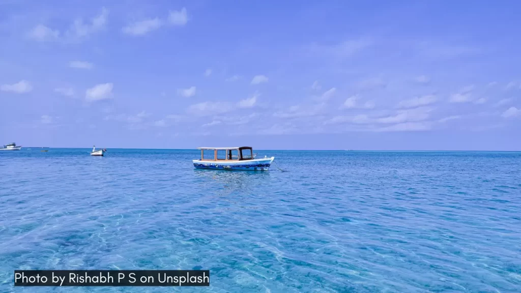 A boat in the azure blue waters of Lakshadweep Islands, one of the best honeymoon destinations in February in India.