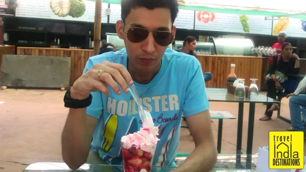 A man enjoying strawberry milkshake at Mapro Garden in Mahabaleshwar, one of the best places to shop in Mahabaleshwar.