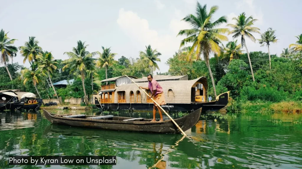 A shot of a man rowing a boat in the backwaters of Alleppey, one of the best places to visit in monsoon in Kerala.