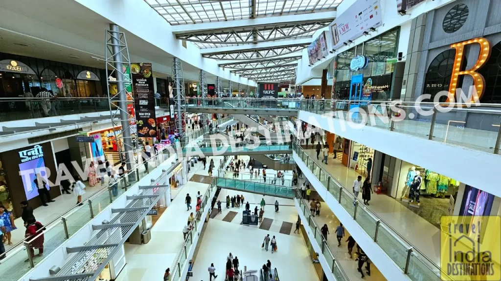 Sunlit interiors of Oberoi Mall Goregaon with glass bridges and a shaded glass roof connecting both ends of the corridor