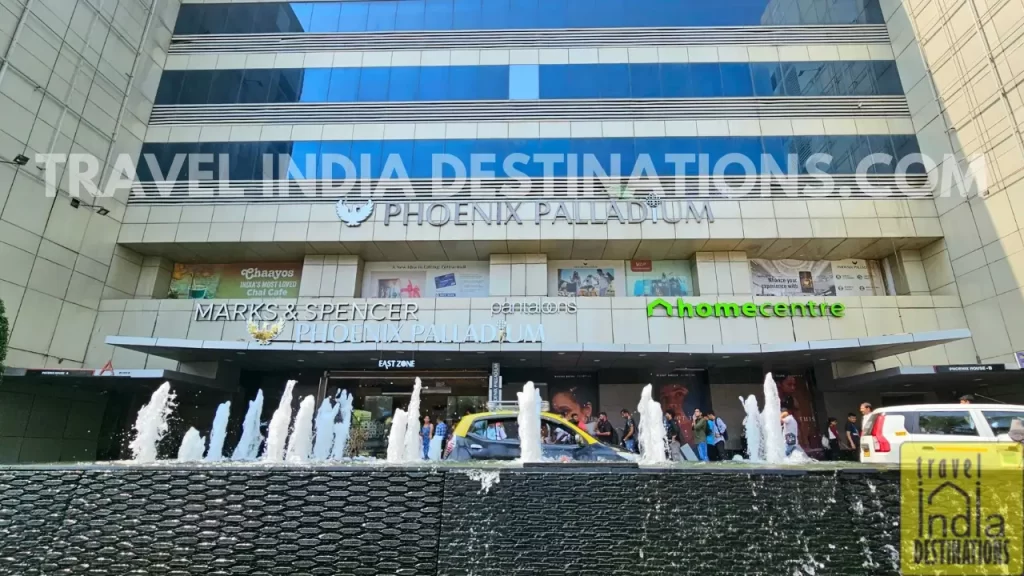 Street-facing view of High Street Phoenix, a luxury shopping mall in South Mumbai, with fountains at the entrance and branded store facades visible