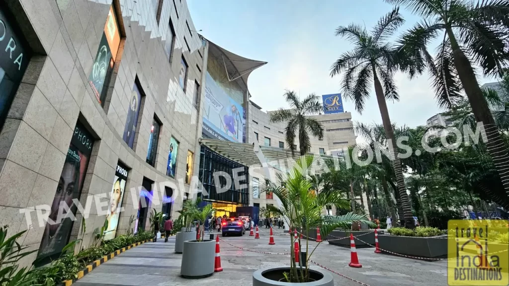 Exterior view of R-City Mall Ghatkopar with lush greenery, parked cars at the entrance, and a glimpse of its vibrant retail facade a popular shopping mall in Central Mumbai