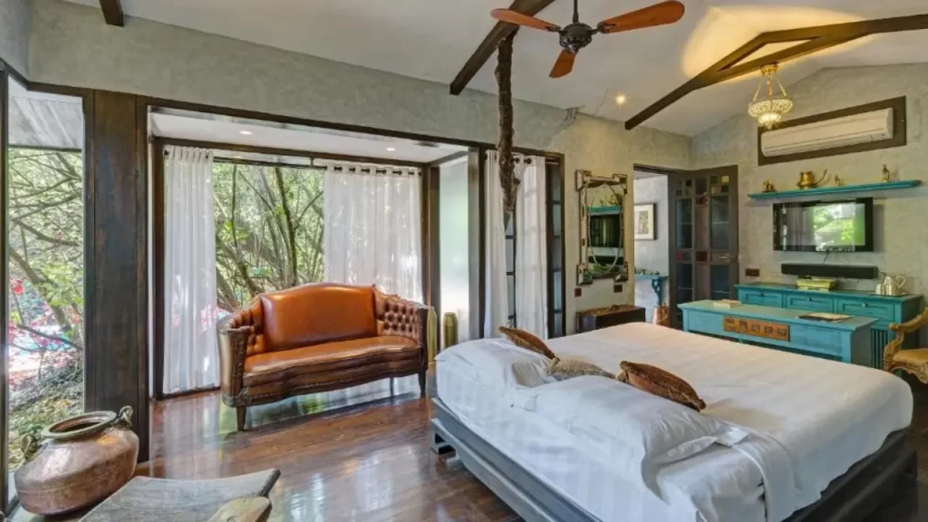 Elegant guest room at Ramsukh Resorts & Spa in Mahabaleshwar with wooden flooring, large windows, and serene forest views