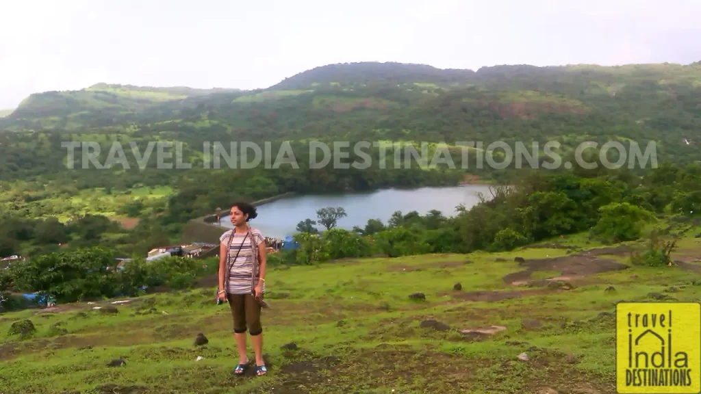 A woman standing on a hill in Lonavala with the backdrop of Bhushi Dam during monsoon season.