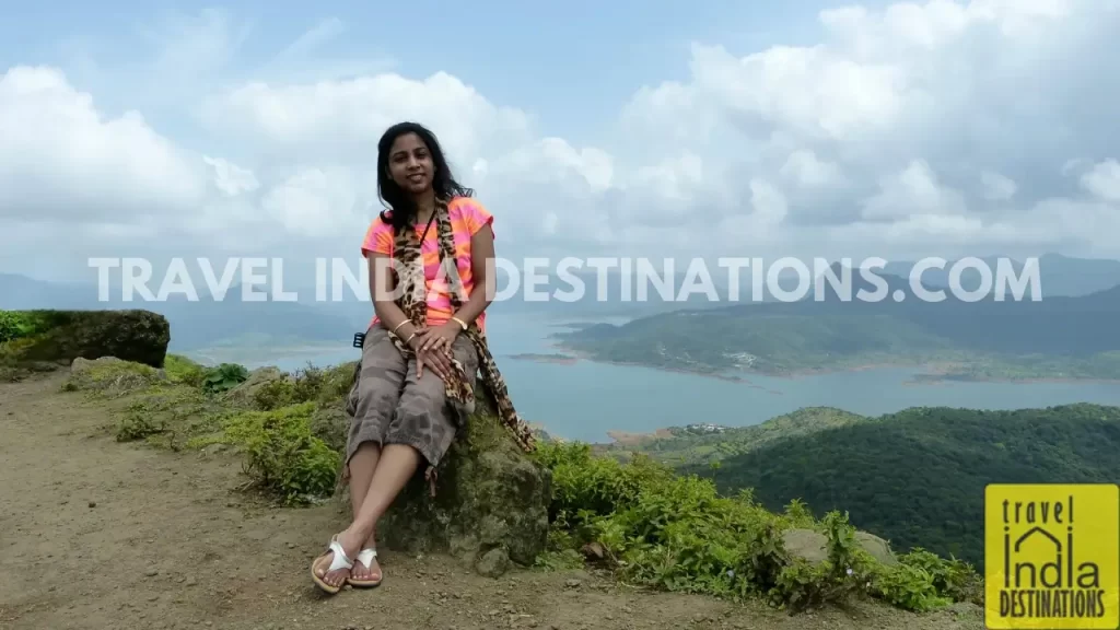 A woman posing at the Lohagad Fort with the backdrop of Pawna Lake.