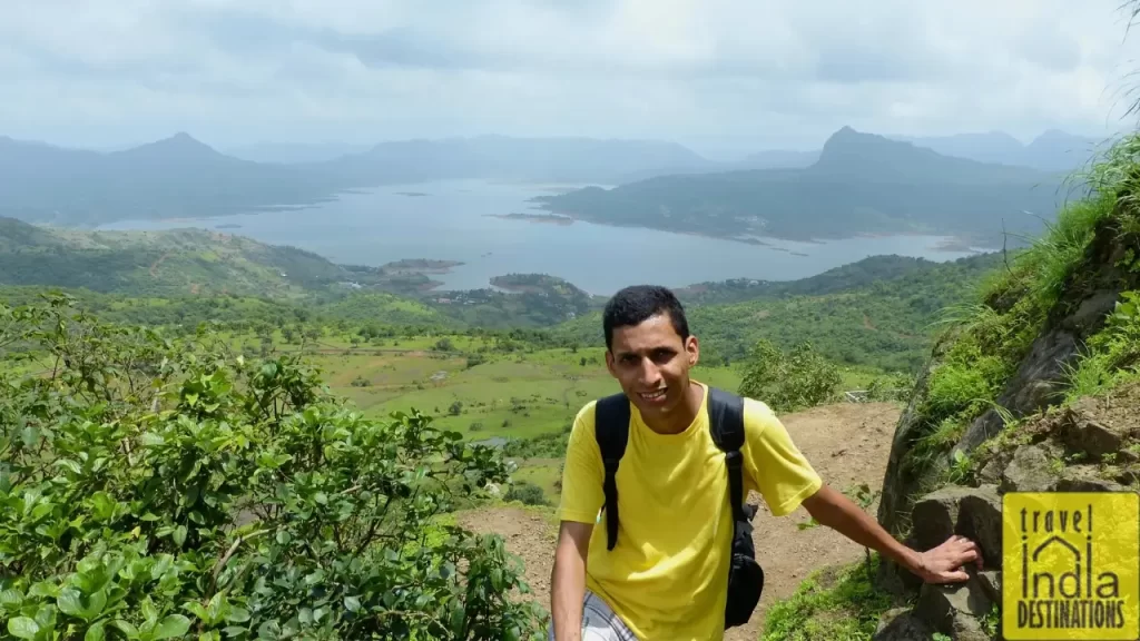 A man trekking the Lohagad Fort near Lonavala with the backdrop of Pawna Lake.
