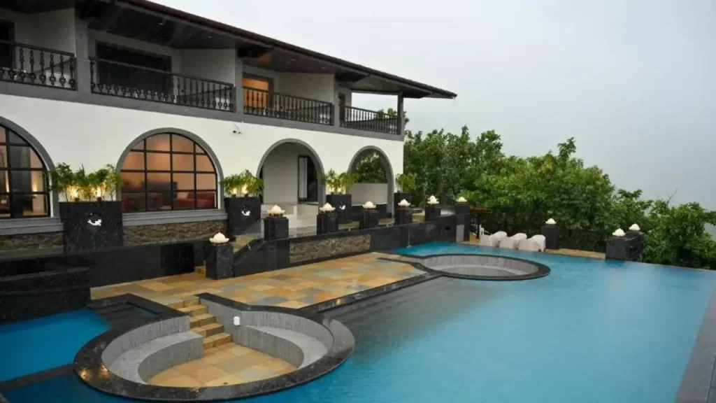 The Green Gate Resort with white and black exterior and outdoor pool is one of the best hotels near ghats in Maharashtra