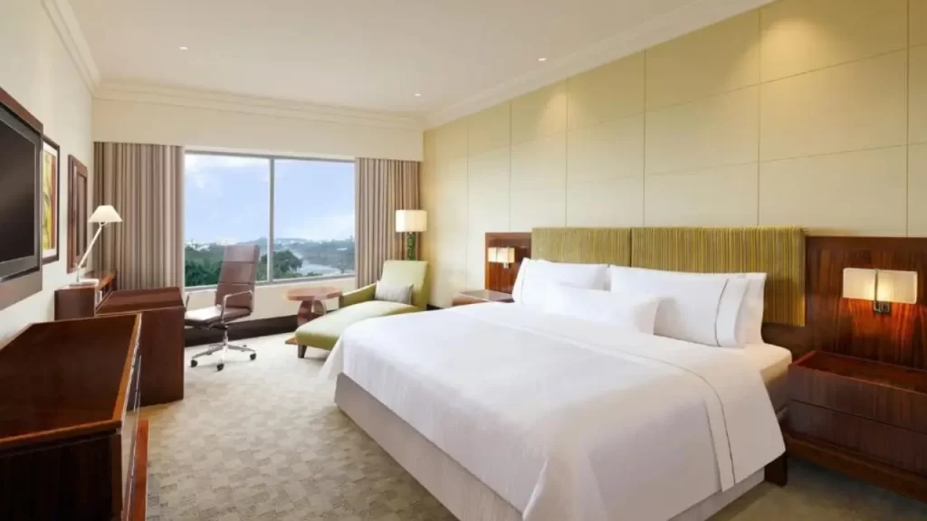 Room at The Westin Pune with white bedding, work desk, armchair, and city view